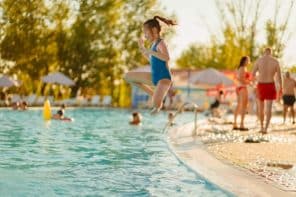 Une adolescente saute dans la piscine d'un des meilleurs campings avec parc aquatique de Bretagne