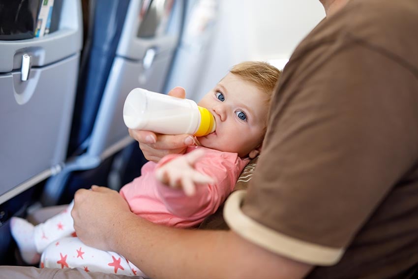 Bébé boit son biberon dans l'avion