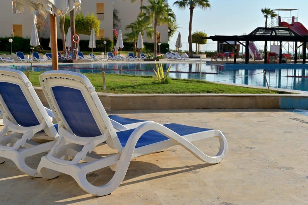 Transats au bord d'une piscine de village vacances avec aire de jeux aquatiques pour enfants