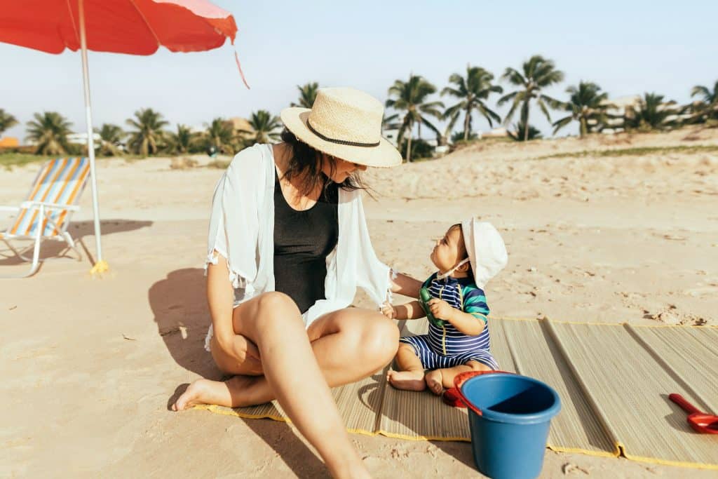 Mère et bébé jouant tranquillement sur la plage sous un parasol