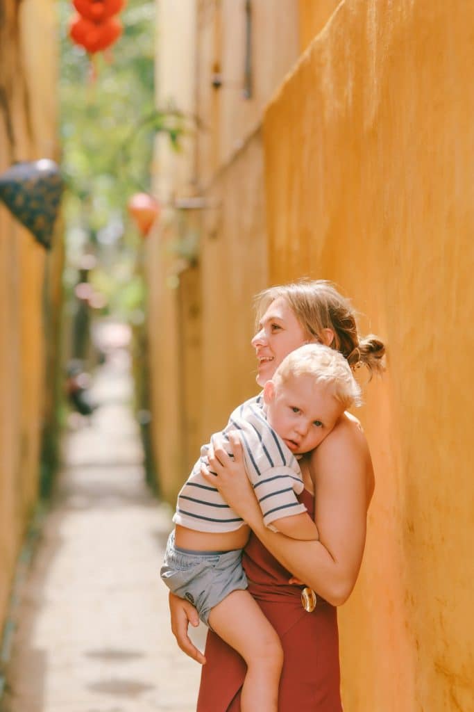 Jeune enfant fatigué dans les bras de sa mère dans une ruelle colorée à l'étranger